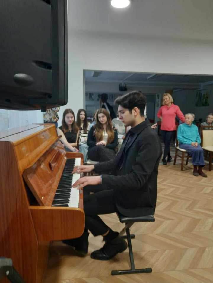 Chłopak grający na pianinie za nim publiczność