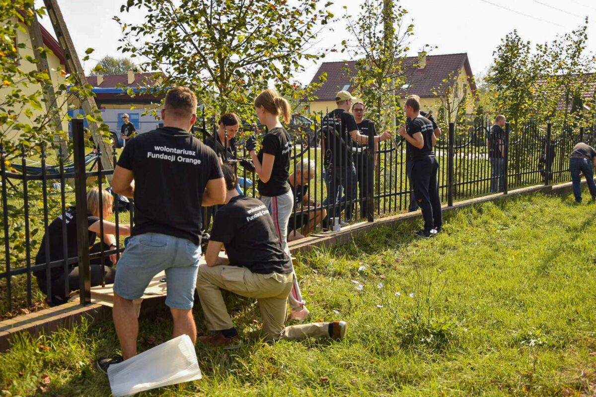 Grupa osób malująca ogrodzenie