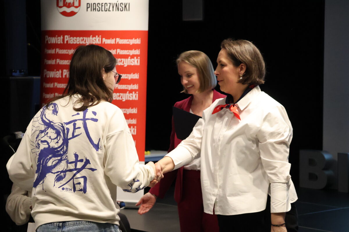 relacja z wydarzenia osoby na scenie skladajace gratulacje